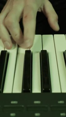 Müzisyenin elleri bir sentezleyici klavyesinde bir melodi çalar. Yakın çekim mor, mavi ve yeşil kulüp ışıklarının değişmesiyle aydınlanır..