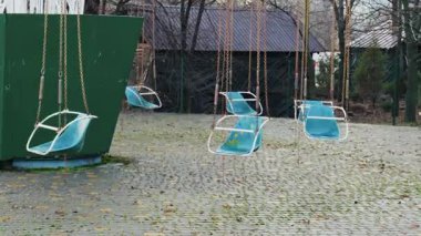 Issız bir parkta hareketsiz duran eski bir atlı karıncaya ait boş mavi salıncaklar. Asfalt zemin, düşen sonbahar yaprakları ve yosunlarla kaplı. Bu da melankolik bir hava yaratıyor..