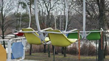 Issız bir parkta sallanan eski bir sandalyenin renkli koltukları. Çıplak ağaçlar ve bir göl kasvetli bir günde melankolik ve ürkütücü bir atmosfer yaratır..