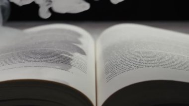 Açık bir kitap kalın, beyaz bir duman tarafından yutulur, sayfalardaki metni gizler. Unutulmuş bilgi kavramı, büyülü hikayeler, ya da bilginin fani doğası.