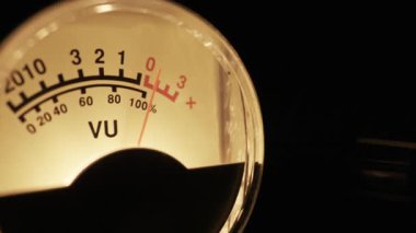 Analog bir VU metre iğnesi ses sinyal seviyesini ölçerken dalgalanıyor. Ses mühendisliği, stüdyo çalışmaları, müzik üretimi ve ses karışımı kavramı.