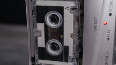 Kırmızı ışıkta parlayan gümüş portatif bir çalgıcının içinde dönen klasik bir ses kaseti. Retro teknoloji kavramı, analog müzik tarihi ve nostaljik medya biçimleri.