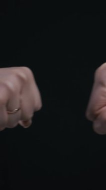 Siyah arka planda izole edilmiş bir yumruk için iki erkek el bir araya gelir. Bu jest, başarılı bir ortaklık, anlaşma ya da dostça selamlaşma kavramını temsil eder..