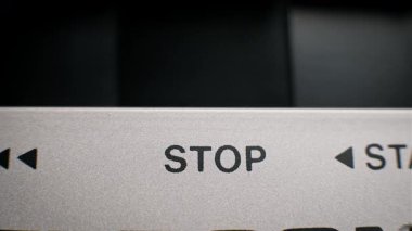 Siyah desenli başlama düğmesine basan bir erkek parmağının uç makro görüntüsü. Bu gümüş metalik kontrol paneli klasik ses ekipmanları ve elektronik aletlerin tipik bir örneğidir..