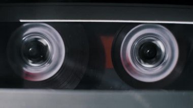 Ses bantlarının aşırı yakın plan görüntüleri klasik bir çalgıcıda hızla geri sarılıyor. Koyu manyetik kurdele makaraları veri depolama ve eski teknolojiyi sembolize etmek için hızla döner.