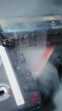 Eskimiş ses kasetleri karanlık bir yüzeyde duruyor. Esrarengiz beyaz duman yavaş yavaş ortadan kayboluyor, eski teknolojiyi karamsar ve serin bir ortamda ortaya çıkarıyor..