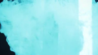 Tek kullanımlık tükenmez kalem, etrafında yoğun bir buhar dalgalanması gibi karanlık bir arkaplanda duruyor. Duman ve cihaz renkli neon ışıklarla aydınlatılıyor..