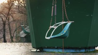 Sonbaharda ıssız bir parkta, eski bir salıncaklı atlıkarıncanın boş koltukları. Kamera yavaşça uzaklaşıyor, melankolik sahneyi yakalıyor ve arka planda sıcak günbatımı ışığı var..