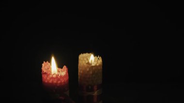 İki desenli balmumu mum, izole edilmiş siyah arka planda parlak alevlerle yanar. Romantizm kavramı, maneviyat, umut ve karanlıkta huzurlu bir rahatlama..