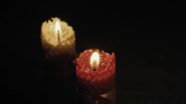 İki balmumu mumundan oluşan yakın plan bir kırmızı ve bir sarı, karanlıkta hafifçe yanıp sönüyor. Barış, maneviyat, romantizm, yas ve sakin ortam kavramı..