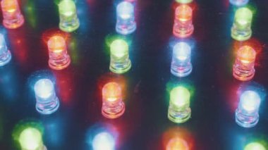 RGB LED ışıkları yanıp sönen bir panelin makro görüntüsü dinamik bir desen içinde renk değiştiriyor. Dijital teknoloji, bilgi gösterimi, enerji ve modern elektronik kavramı.