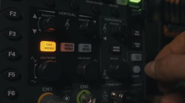 Dijital osiloskopun el ayarlaması kontrolleri, sinyal analizi için cihazı kalibre ediyor. Elektrik mühendisliği, bilimsel araştırma ve hassas tanı kavramı.