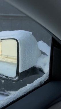 Beyaz bir arabanın yan aynası kalın kar ve buz saçaklarıyla kaplıdır. Pencereden izlerler. Kavram, soğuk hava koşullarının yol açtığı tehlikeleri ve kış bakımını temsil ediyor.