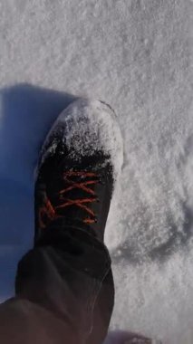 Yoğun taze karda ağır ağır yürüyen siyah yürüyüş botlarının birinci şahıs görüntüsü. Kış vahşi doğa keşfi, açık hava macerası ve soğuk sezon yürüyüşü kavramı..