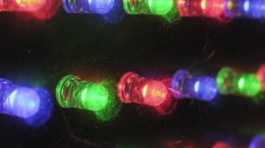 Flaşlı RGB diyotları olan elektronik panelin makro yakın çekimi. Siyah bir yüzeye karşı kırmızı, yeşil ve mavi ışıklardaki toz parçacıklarını ortaya çıkaran bir askı odağı bulanıklıktan keskinliğe gider.