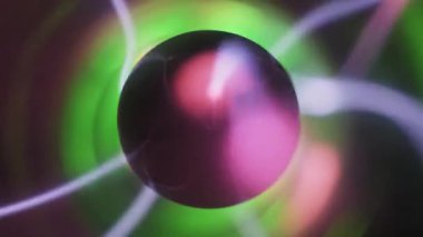 Merkezi bir siyah elektrottan çıkan pembe ve beyaz cıvatalı bir plazma küresinin yakın çekimi. Yeşil iyonize gaz akımları ve elektrik yayları cam küre içinde hareket ediyor.