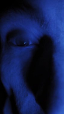 Aşırı yakın çekim erkek gözlerinin genişlediğini ve etrafa çılgınca baktığını gösteriyor. Doymuş mavi ışık paranoyak ve gerçeküstü bir bilim kurgu atmosferi yaratır..