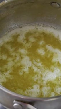 Sıcak altın eritilmiş tereyağı paslanmaz çelik bir tencerede güçlü bir şekilde kaynıyor ve köpürüyor. Mutfak hazırlığı kavramı, açık kahve ve otantik pişirme tarifleri..