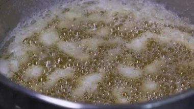 Sıcak altın sebze yağı paslanmaz çelik bir tencerede kaynıyor ve kabarcıklar pişerken yüzeye çıkıyor. Sağlıksız kolesterol, yağlı yemek pişirme ve aşçılık hazırlığı kavramı