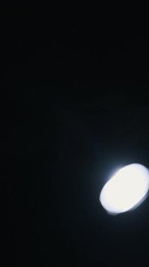 Parlak dairesel bir ışık karanlık bir arkaplan üzerinde düzensizce hareket eder, keskin mavi mercek parlamaları ve parlak çizgiler yaratır. Bu soyut dikey görüntü sinyal veya arama kavramlarına uyar.