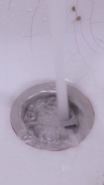 Akan su akışını kapatır ve beyaz seramik lavaboya dökülür ve yüzeyde çatlaklar oluşur. Temiz sıvı, tamamen boşalana kadar metal borulardan aşağı süzülür. Suyun korunumu kavramı.