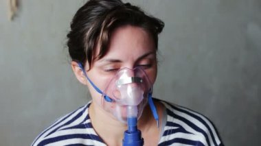 Woman wears a mask for inhalation, and conducts the procedure lungs inhalation using a nebuliser.