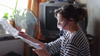 Woman wears a mask for inhalation, and conducts the procedure lungs inhalation using a nebuliser.