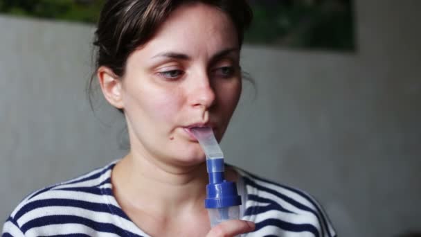 Woman wears a mask for inhalation, and conducts the procedure lungs inhalation using a nebuliser. — Stockvideo