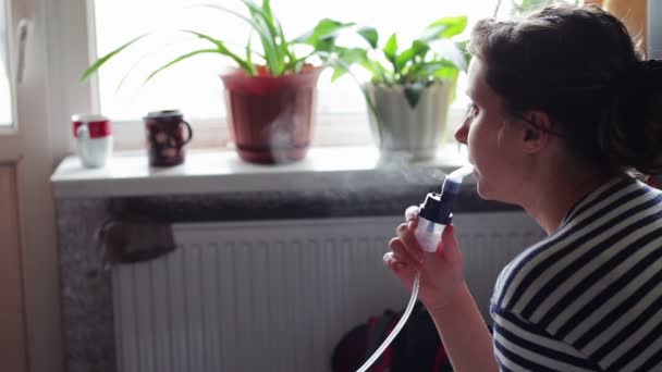 Mulher usa uma máscara para inalação e realiza o procedimento inalação dos pulmões usando um nebulizador . — Vídeo de Stock