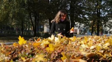 Mutlu kız sonbahar park ve toplar sarı yürüyüş yaprakları düşmüş.