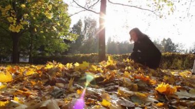 Ağaçlar sonbahar Park ağaç dalları gelen sarı yapraklar kız atıyor.