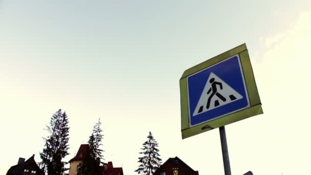 Panneau de la traversée piétonne sur fond ciel et maisons .