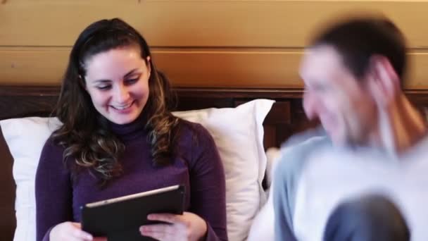 Feliz hombre y mujer con la tableta en la cama . — Vídeo de stock