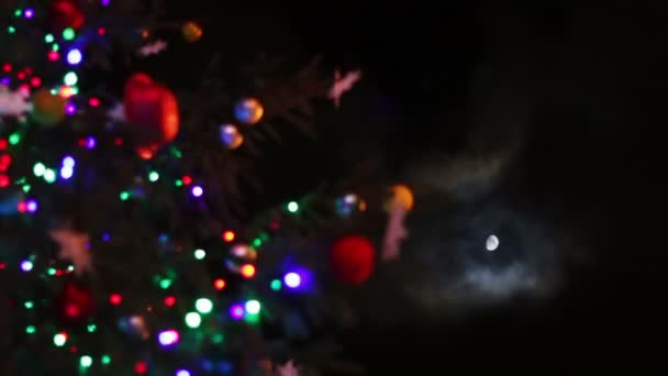 Kerstboom versierd met speelgoed en lichten 's nachts op een achtergrond van de maan. — Stockvideo