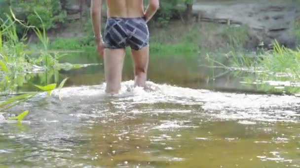 Een man loopt in het water van de rivier. — Stockvideo