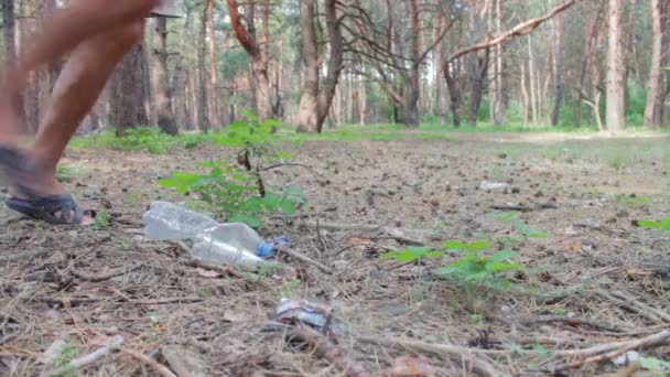 Homem bate pé garrafa de plástico na floresta . — Vídeo de Stock