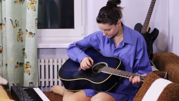 Young beautiful girl learning to play the guitar at home. — 비디오