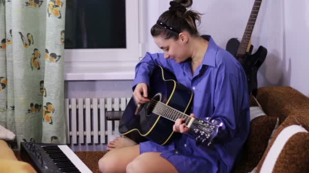 Young beautiful girl learning to play the guitar at home. — 비디오