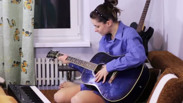 Jovem menina bonita aprendendo a tocar guitarra em casa . — Vídeo de Stock