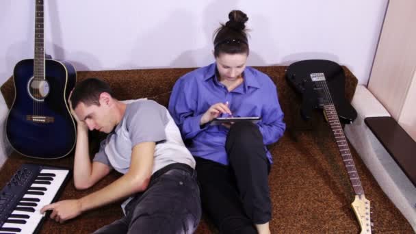 Ευτυχισμένο νεαρό ζευγάρι χρησιμοποιώντας tablet PC και να παίξει πιάνο — Αρχείο Βίντεο