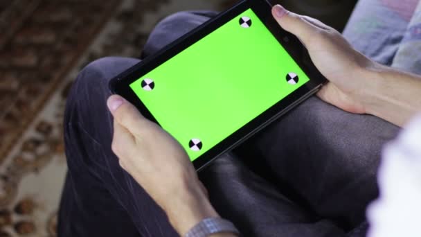 Hombre usando Tablet Computer en el sofá con pantalla verde — Vídeo de stock