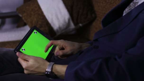 Homem usando computador tablet no sofá com tela verde — Vídeo de Stock