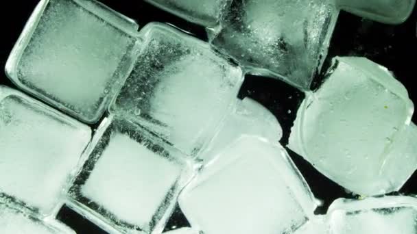 Cubo de hielo derritiéndose y moviéndose sobre una superficie de vidrio — Vídeo de stock