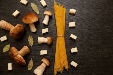 Beyaz orman mantarları, baharatlar, spagetti ve peynir parçalarıyla kaplanmış. Tahta masadaki taze mantarlar..