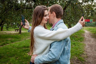 Genç bir çift parkta birlikte vakit geçirir, birbirlerine sarılırlar ve telefonlarına bakarlar. Parkta aletleri olan bir kızla birlikte olan adam.