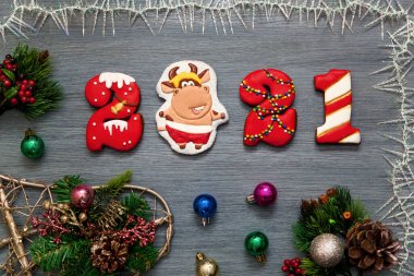 Tatil için bir Noel kartı. 2021 numaralı zencefilli çörek ve gri ahşap arka planda yeni yıl boğasının sembolü. Mutlu Noeller ve yeni bir yıl.