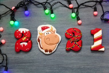 Tatil için bir Noel kartı. 2021 numaralı zencefilli çörek ve gri ahşap arka planda yeni yıl boğasının sembolü. Mutlu Noeller ve yeni bir yıl.