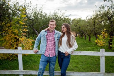 Birbirine aşık çiftler sonbahar parkında birbirlerine sarılıyorlar. Parktaki genç çift.