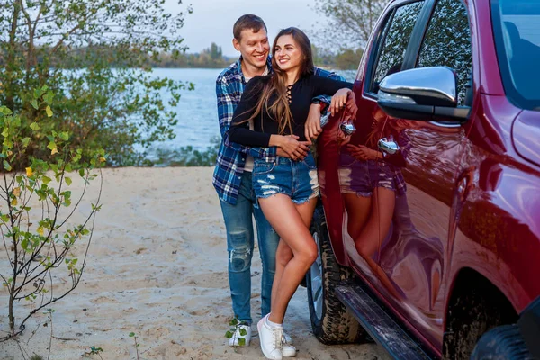 Szczęśliwa Młoda Para Zakochana Uśmiechnięta Przytulona Obok Czerwonego Samochodu Plaży — Zdjęcie stockowe