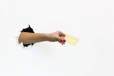 Kırmızı manikürlü, yırtık beyaz kağıtlı bir kadının elinde altın bir kredi kartı var. Yırtık beyaz kağıtlar arasında